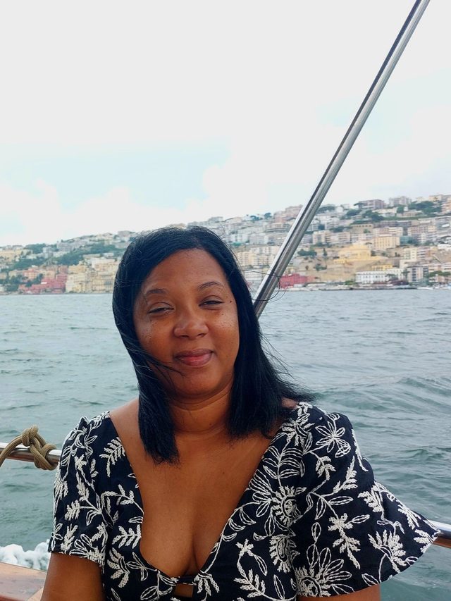 Tamica on a boat with the Italian coastline behind her