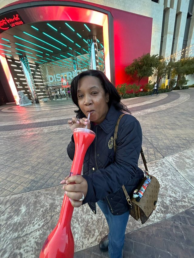 Tamica sipping an oversized red drink outside a casino entrance in Las Vegas